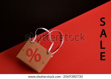 A paper bag with a percentage sign on a black and red background