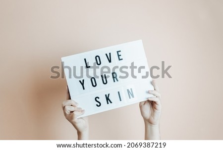 Hands holding a sing with love your skin written in it, minimal desaturated background, indie style, modern design, banner with copy space, motivational speech