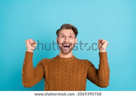 Photo of positive charming happy young man raise fists winner celebrate isolated on blue color background