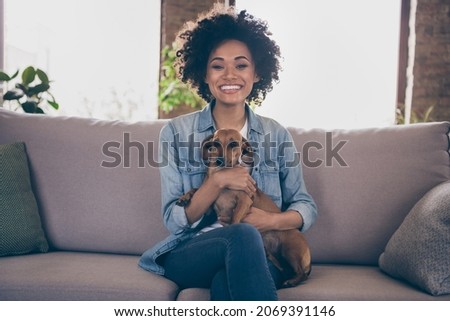 Photo of young cheerful african couple happy positive smile hug animal pet best friend dog sit couch indoors