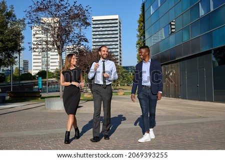 three business people walking down the street and laughing after workday Royalty-Free Stock Photo #2069393255