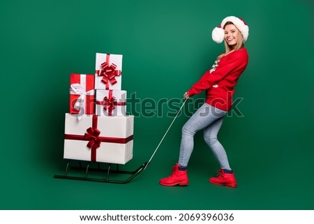 Full length body size view of attractive cheerful girl wearing Santa look carrying many giftboxes isolated over green color background