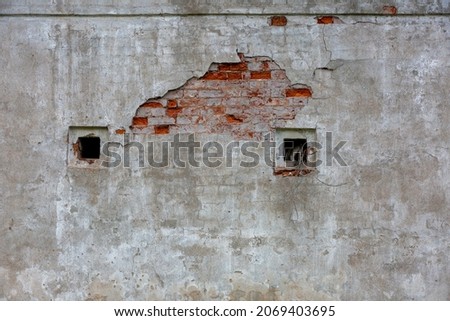 fragment of the whiteeashed briks wall of old building with the spot of  red briks oand three strange wholes Royalty-Free Stock Photo #2069403695