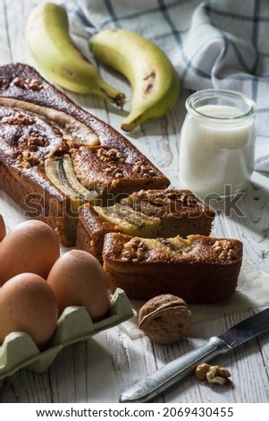 A banana cake with some ingredients like eggs, nuts, milk and bananas. backlighting. sponge cake. vertical image.