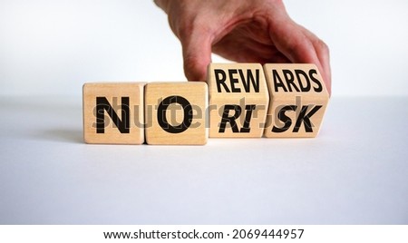 No risk or rewards symbol. Businessman turns wooden cubes and changes words 'no risk' to 'no rewards'. Beautiful white background. No risk or rewards and business concept. Copy space.