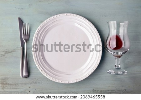 White plate with glass of wine and exotic spices and fruits on light blue wooden table. Flat lay