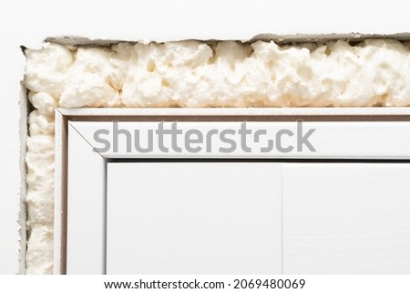 Installation of an interior door with fixation on polyurethane foam. Installing polyurethane foam around the door, close up. Royalty-Free Stock Photo #2069480069