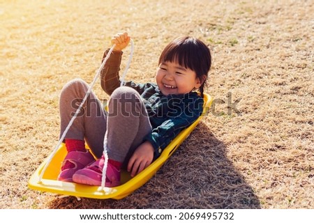 Girl playing grass sliding outdoors.