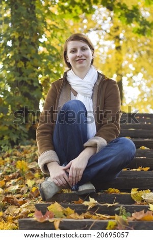 Portrait of young beautiful red-haired women sitting on the stairs in the park and smiling