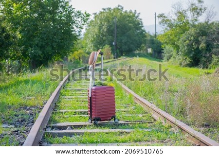 a red suitcase and a hat on the railroad stands. High quality photo