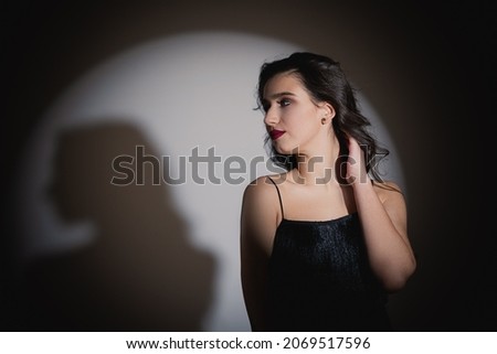 The girl looks away. Studio photo of the model. Shadow of a girl on a white background. Thick and wide eyebrows.