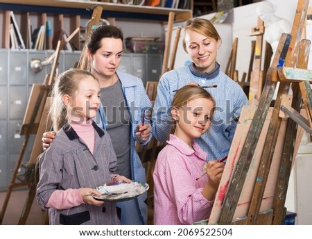 happy skillful young students looking at progress of fellow student during painting class
