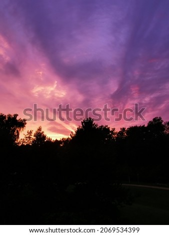 Purple clouds and sunset coming behind a mountain.