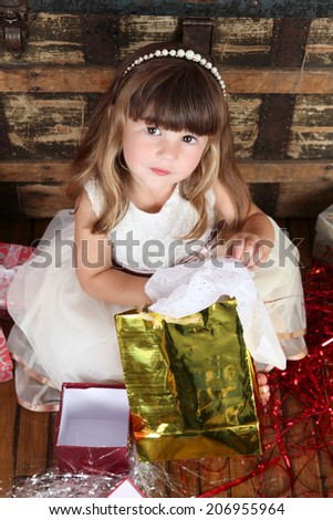 Little girl in a dress opening christmas gifts