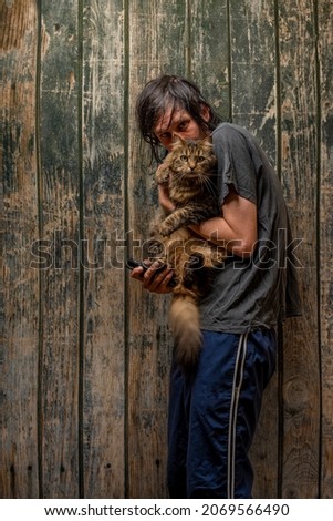 Black hair man with tabby small cat near wooden old wall