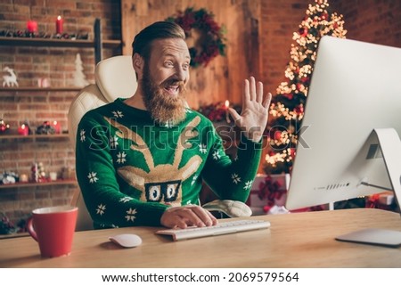 Photo of positive freelancer bearded ginger man sit desk wave hand conference wear sweater decorated office indoors