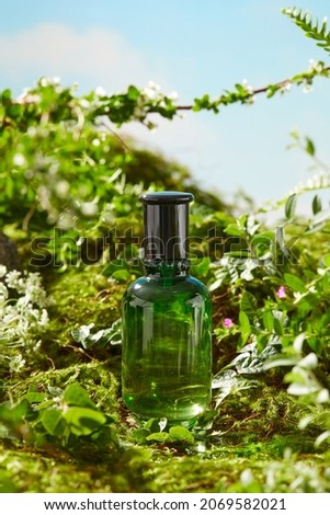 Front view of green cosmetic jar in a garden with flower , green leaf rocks bright daylight background , reflection of a lake photography nature conconcept