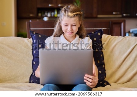 Child girl with laptop at home on the couch