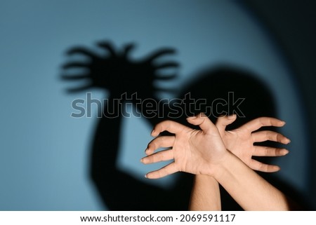 Woman making shadow spider with her hands on color background
