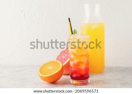 Glass of tasty Tequila Sunrise cocktail on light background