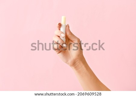 Female hand with natural lip balm on color background Royalty-Free Stock Photo #2069609528