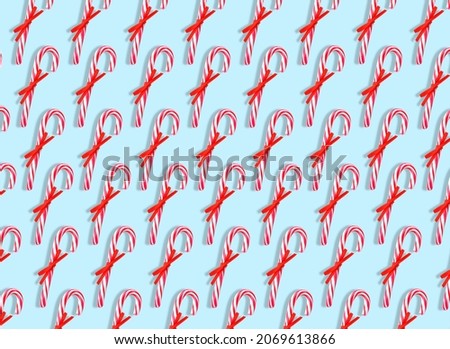 Many candy canes on light blue background. Pattern for design