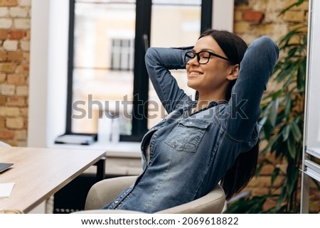 Photo of happy satisfied brunette woman resting in comfortable chair enjoying peace and relaxation break at workplace