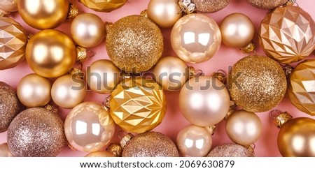 Festive pink background with gold and silver Christmas balls. Flat lay, top view.