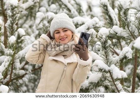 woman takes selfie in the snow covered forest during a winter adventure.