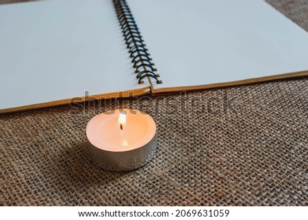 candlelight with notebook on burlap background, writing on notebook under candlelight, sketch book in candlelight environment