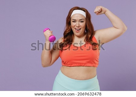 Young chubby overweight plus size big fat fit woman 20s wear red top warm up training with dumbbells show biceps muscles power isolated on purple background home gym Workout sport motivation concept