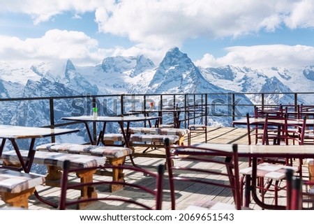 An open-air cafe high in the snow-capped mountains on a clear, sunny day. Winter sports and outdoor activities.