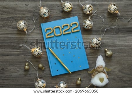 Planner and Christmas decor on wooden background, flat lay. 2022 New Year aims