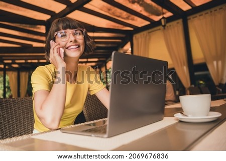 Photo of shiny positive lady dressed yellow t-shirt glasses sitting cafeteria drinking coffee talking modern gadget outdoors urban park Royalty-Free Stock Photo #2069676836