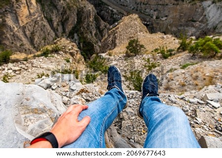 View of the feet of a male traveler in sneakers on a hilltop enjoying the view