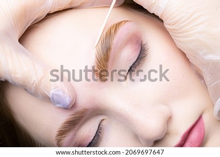 close-up alignment of the contour of the eyebrows with a cotton swab after the procedure lamination and coloring of the eyebrows Royalty-Free Stock Photo #2069697647