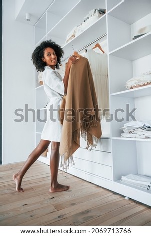 With different clothes. Young african american woman with curly hair indoors at home.