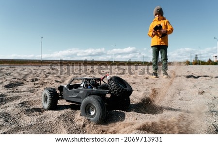 Boy kid playing radio control car riding on sand outdoor enjoying happy childhood Royalty-Free Stock Photo #2069713931