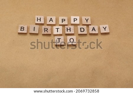 HAPPY BIRTHDAY TO spelled with wooden letter tiles isolated on brown background with copy space