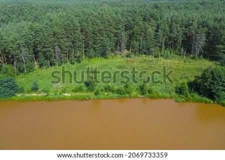 The water reservoir is located in the forest. After heavy rainfall, the water turns brown. View from the dron