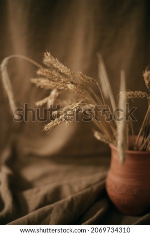 Ceramic brown jug with a bunch of ears of corn. Picture of a rural life.