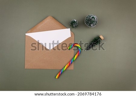 A blank white sheet in a craft envelope next to small Christmas trees.