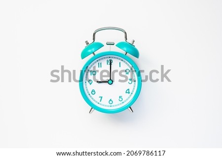 Modern alarm clock in retro style on cyan color batteries isolated on white background. Time and morning concept. Flat lay Royalty-Free Stock Photo #2069786117