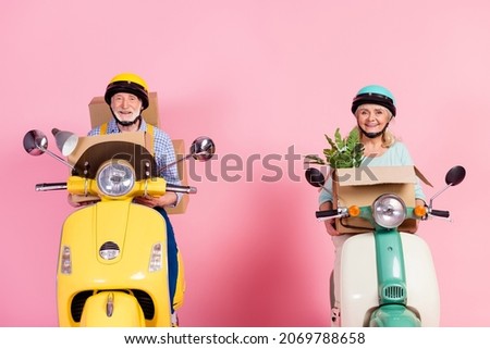 Photo of funky excited senior husband wife driving motorbike dressed helmets carrying staff new home isolated pink color background