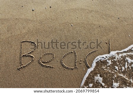 on the beach is carved with letters in the smooth sand the writing Beach