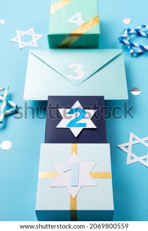 Hanukkah traditional eight nights of light. Gift boxes, stars of David and white candles on blue paper background. Jewish holiday Hanukkah concept. 