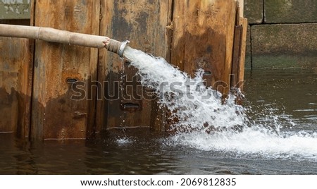 pumping water with a fire hose. fence in the water. advertising picture. repair of the embankment on the river.