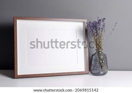 Landscape wooden frame mockup for artwork, photo and print presentation with dry laverder flowers in vase. Minimalist interior design.