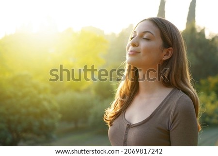 Happy woman breathing fresh air against natural background. Copy space.