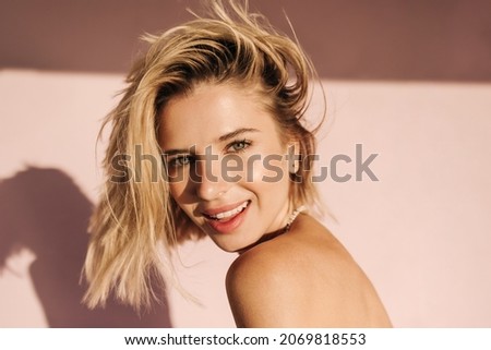 Close up portrait of fair skinned young woman looking at camera with mouth open. Blonde with short hair on one side on pink background with bare shoulders. People sincere emotions lifestyle concept. Royalty-Free Stock Photo #2069818553
